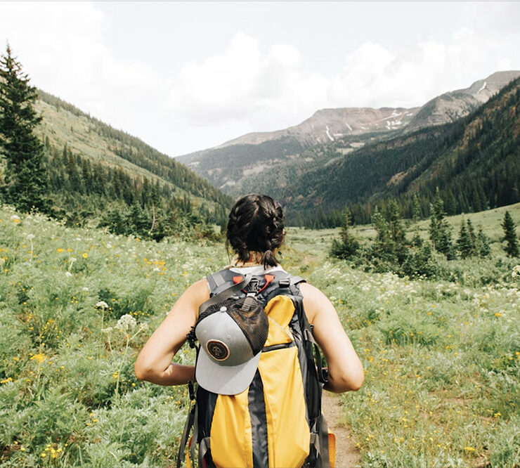 Adventure traveller gazing at a meadow and distant mountains