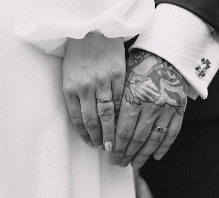 Newly married wedding couple holding hands, with new wedding rings