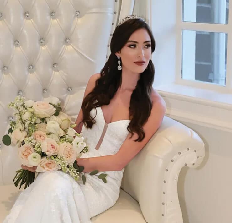 Bride seated on a luxurious couch, holding a pastel floral bouquet