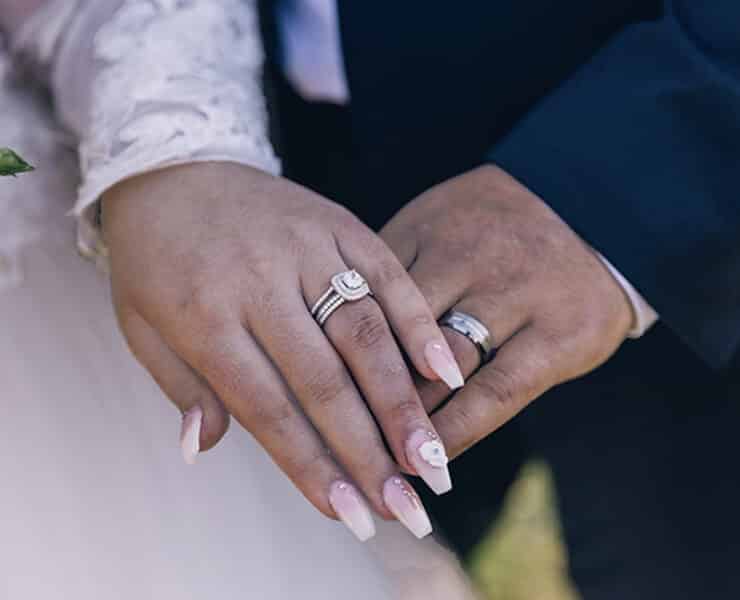 Newlyweds holding hands and siplaying their new weddings rings