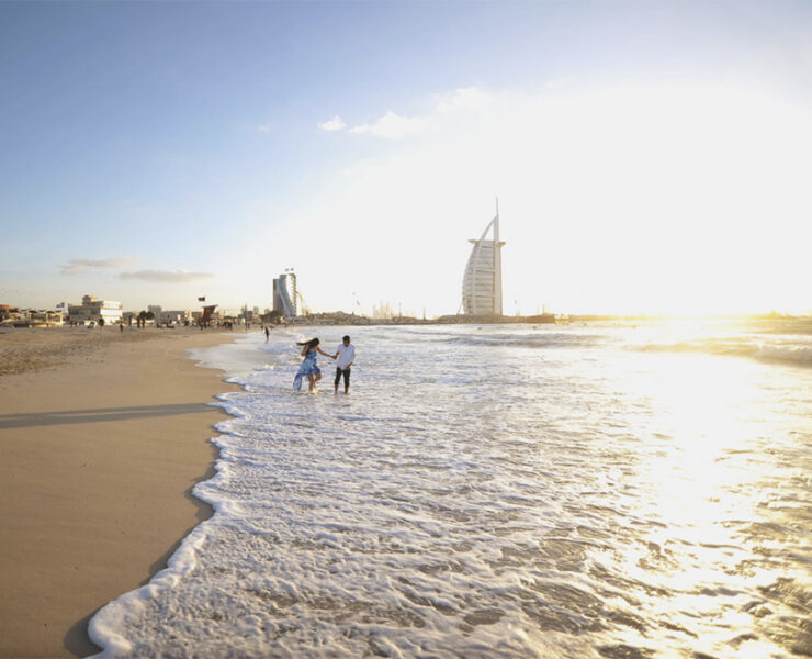 Playful couple on the beach in Dubai, by the water's edge