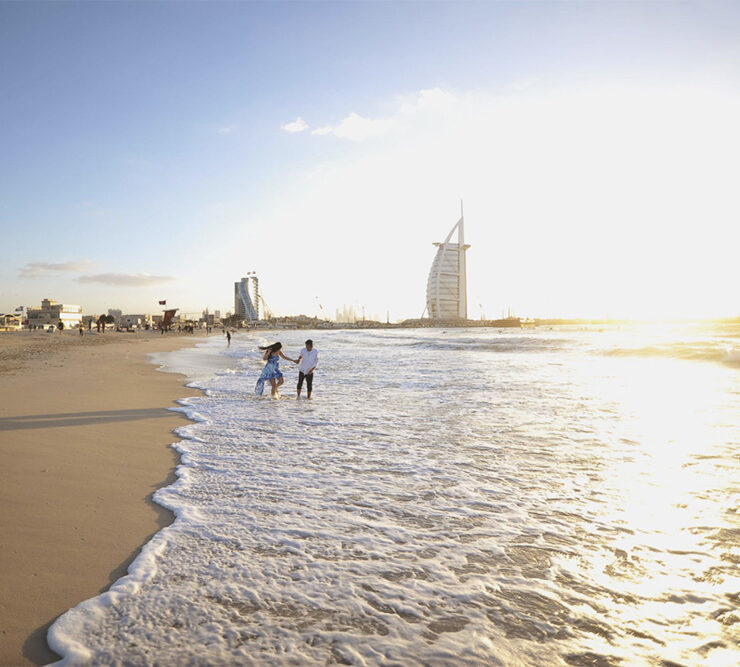 Playful couple on the beach in Dubai, by the water's edge