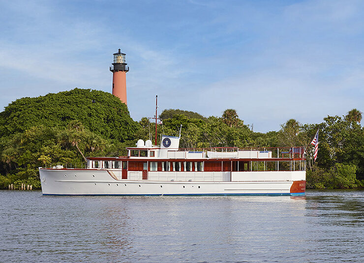 Outdoor view of Honey Fitz Yacht, passing by a picturesque lighthouse